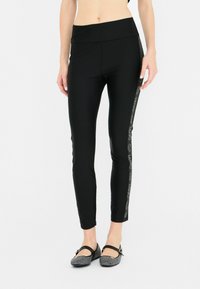 Leggings neri con vita alta, caratterizzati da una banda laterale con dettagli del logo e una silhouette aderente. Tessuto liscio e elastico.