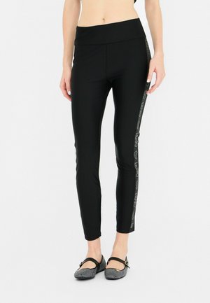 Zwarte legging met een hoge tailleband, voorzien van een zijstreep met logo-detail en een aansluitende pasvorm. Zachte, rekbare stof.
