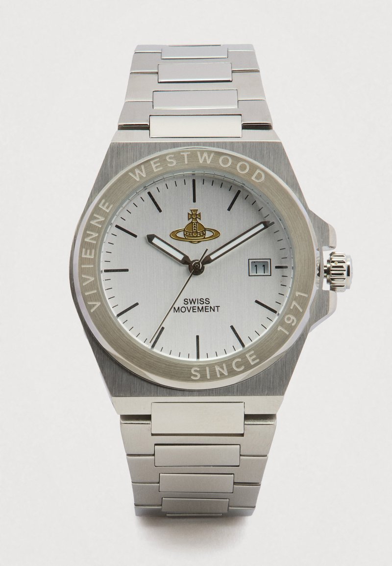 Sudraba krāsas nerūsējošā tērauda Vivienne Westwood pulkstenis ar baltu ciparnīcu, melniem stundu rādītājiem, datuma logu un trim rādītājiem, kas rāda 10:10:40.