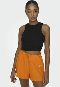 Zwarte geribbelde crop top zonder mouwen, gecombineerd met oranje shorts met trekkoord en geborduurde tekst "Los Angeles".