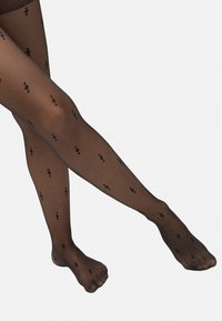 Medias negras con un acabado transparente, que presentan un patrón de pequeños rombos y puntos negros, destacando una textura suave y un diseño ajustado.