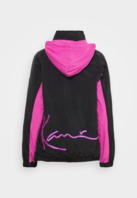 Veste noire avec capuche rose et panneaux latéraux, avec texte de signature brodé rose sur le bas du dos.