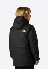 Black insulated jacket with a hood. Features a vertical seam and a logo on the upper back. Smooth texture with a slightly puffy design.