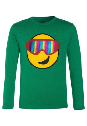 Grøn langærmet skjorte med et stort gult smiley-ansigt iført regnbuefarvede ski goggles og et legende smil på forsiden.