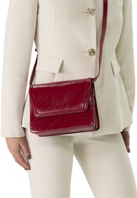 Rote Leder-Crossbody-Tasche mit rechteckiger Form, Klappverschluss und schmalem Riemen, mit glänzender Oberfläche und subtiler Textur.