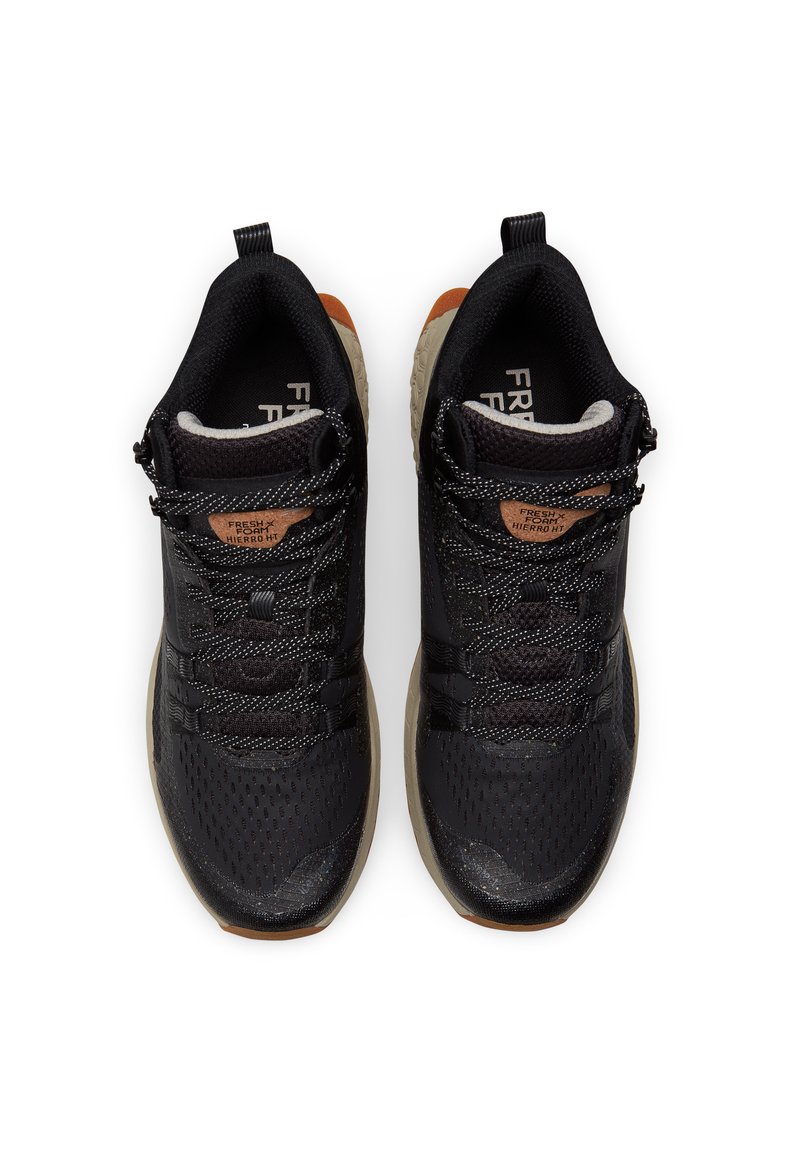 Zwarte sportschoenen met een bovenwerk van mesh, een gestructureerd ontwerp en reflecterende veters. Rubberen zool, bruine accent op de hak en logo op de tong.