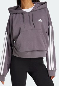 Szara, krótką bluza z kapturem, wykonana z miękkiego materiału, z przednią kieszenią, zamkiem błyskawicznym oraz białymi, potrójnymi paskami na rękawach.