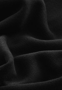 Tissu tricoté noir avec une texture douce et lisse, présentant de légers plis et un motif uniforme sur toute la surface.