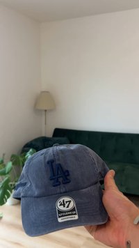 Tumesinine teksariidest pesapallimüts, millel on tikitud "LA" logo, reguleeritav rihm ja kumer visir.