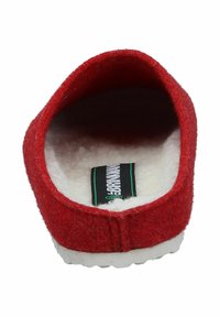 Red felt slipper with a soft white fur lining, rounded back, and a white rubber sole. Interior label visible. Simple, cozy design.