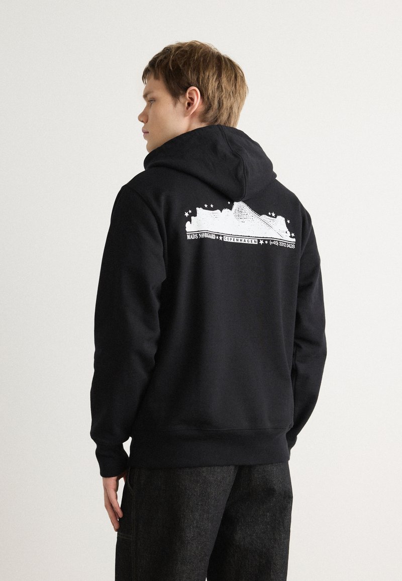 Sudadera negra con un estampado texturizado en la parte posterior que presenta el horizonte de Copenhague y estrellas. Tejido suave, capucha con cordón y puños acanalados.