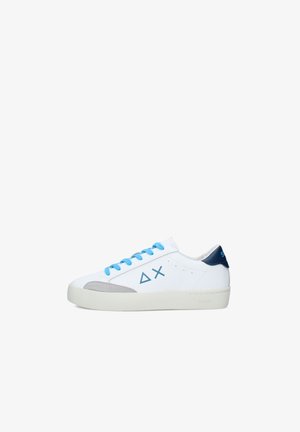 Baskets blanches basses avec des lacets bleus, des logos géométriques bleus sur le côté, un détail gris à l'avant et un renfort de talon bleu marine sur un fond blanc.