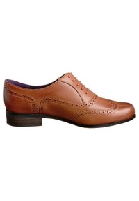 Chaussure habillée Oxford pour homme en cuir marron avec détails brogue, fermeture à lacets et petit talon empilé, présentée de profil sur fond blanc.