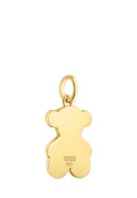 Złota zawieszka w kształcie misia z polerowanym wykończeniem, z przymocowaną pętlą do zawieszenia. Na odwrocie oznaczona napisami "TOUS" i "S925".