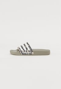 Adidas flip-flops i oliven grønn med et mønstrete stropp som har hvite tre-striper og logo. Laget av mykt, fleksibelt materiale.