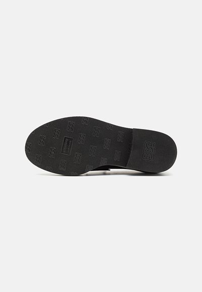 Sort sneakersål med tekstureret gummi, der har logoaftryk og en holdbar, skridsikker overflade. Formen er afrundet ved tåen og hælen.