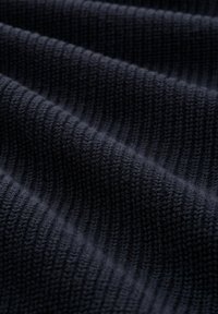 Dunkelblaues gestricktes Gewebe mit gerippter Textur, das gleichmäßige Reihen von Stichen zeigt und eine weiche, leicht verschwommene Oberfläche hat.