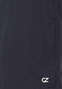 Marinblå, lätta shorts i texturerat tyg, med en vit "CZ"-logotyp vid fållen och sidofickor.