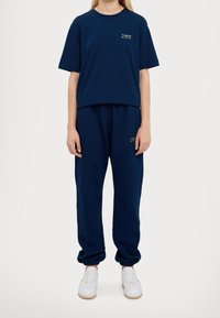 Marineblauwe katoenen t-shirt met een ronde halslijn en korte mouwen, gecombineerd met bijpassende jogger pants met een elastische tailleband en manchetten.