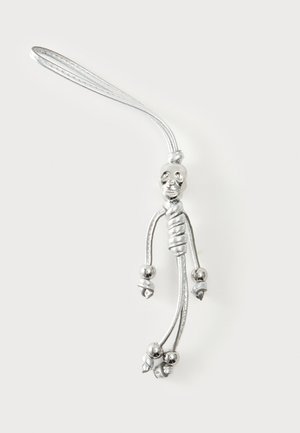 Porte-clés squelette métallique argenté avec sangle en boucle, tête de crâne détaillée, torse enroulé et membres noués terminés par des perles rondes.