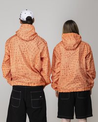 Orangemusterte Jacken mit Kapuzen, die ein geometrisches Quadratdesign aufweisen. Sie sind über schwarzen Shorts getragen, wobei die elastischen Bundenden am unteren Rand sichtbar sind.