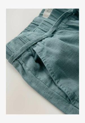 Lyseblå linnedrennede shorts med en samlet elastisk talje, forlommer og snore i stoffet. Glat struktur med synlige stikninger.