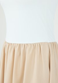 Bodice ajusté blanc avec une jupe beige plissée. Tissu lisse et léger avec une texture douce et un éclat subtil. Design simple.