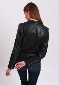 Black leather jacket with a fitted design, prominent shoulder seams, and zippered cuffs. Smooth texture, back view focusing on tailoring details.