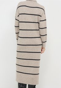 Abito in maglia beige con strisce orizzontali nere, maniche lunghe, colletto alto e vestibilità dritta, che arriva a metà polpaccio.
