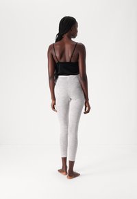 Black spaghetti strap tank top paired with light gray, fitted, high-waisted leggings. Smooth texture, minimal design, no visible patterns or accents.