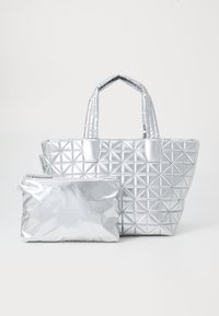 Srebrna torba na ramię o geometrycznym wzorze z dwoma krótkimi uchwytami i pasującą, zapinaną na zamek saszetką. Wykonana z błyszczącego, metalicznego materiału.