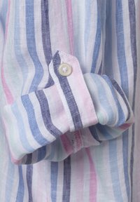 Multicolored striped fabric shirt with blue, pink, and white stripes. Features a button on the cuff and a textured linen appearance.