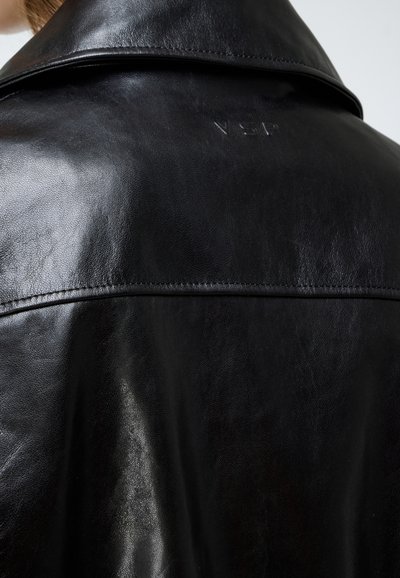 Black leather jacket featuring a smooth, shiny texture, notched collar, and embossed logo on the back. Simple stitching along seams.