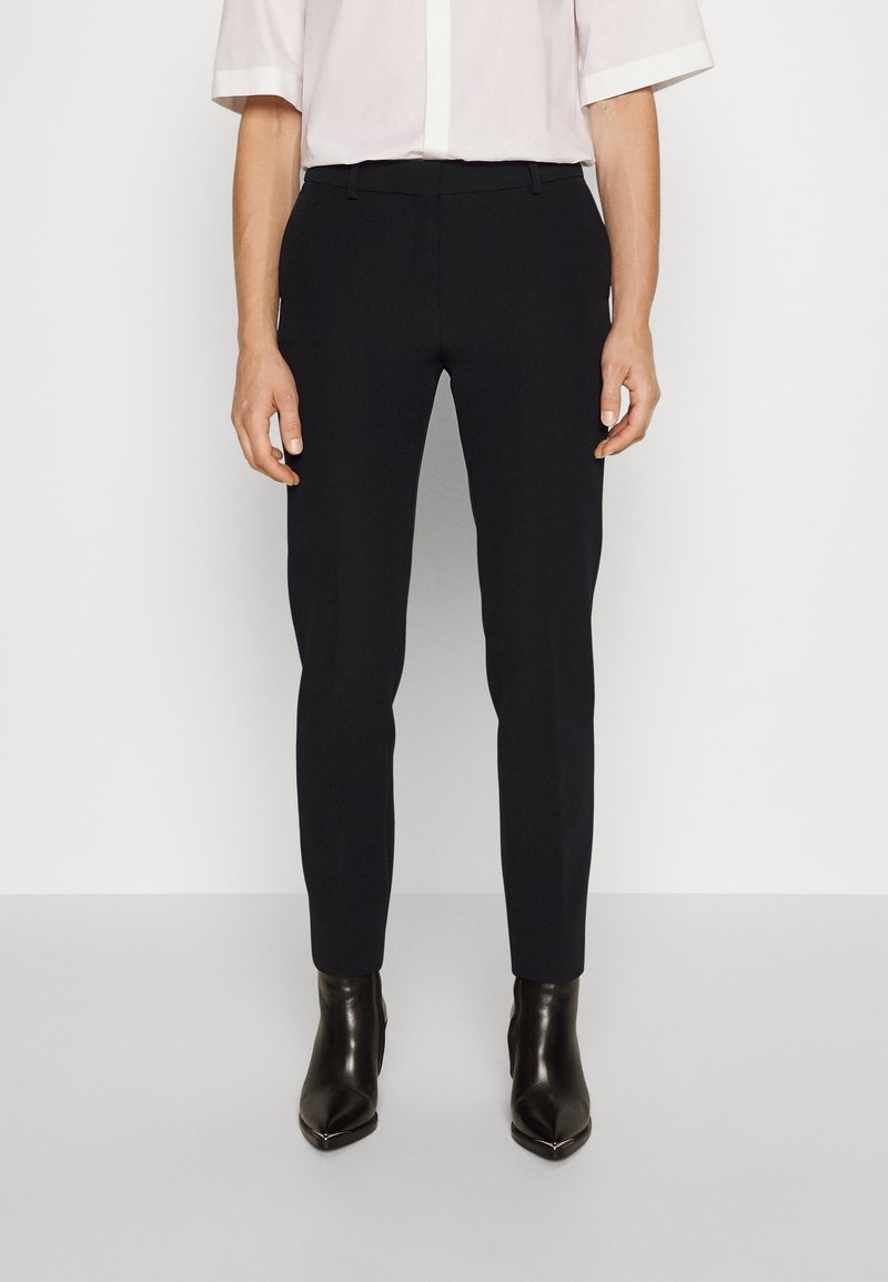Svarta skräddarsydda byxor med slim fit, tillverkade av slät tyg, med midjeband, bältesöglor och en ren finish. Bärs med ankelstövlar.