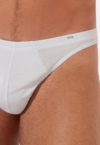 Weiße Baumwollunterwäsche mit nahtlosem Design, weicher Textur und kleinem Markenetikett am Bund.