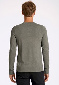 Szary sweter z długim rękawem, okrągłym dekoltem oraz ściągaczami przy mankietach i dolnym brzegu. Gładka faktura, dopasowany krój.