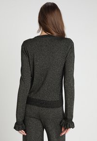 Zwart, glinsterend trui met lange mouwen, een aansluitend silhouet, gerimpelde manchetten en een geribde zoom, ontworpen in een glinsterende textuur.