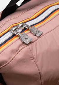 Borsa di stoffa rosa con cerniera bianca e una striscia multicolore, con cursori metallici e marchio. Superficie texturizzata con cuciture visibili.