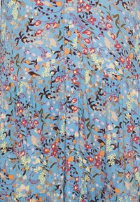 Modrá látka s hustým květinovým vzorem v červených, oranžových, žlutých, růžových a hnědých tónech, se shromážděnými švy a detaily šití.