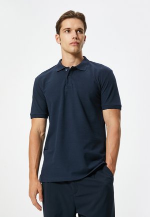 Polo de color navy hecho de algodón, con un cuello clásico, tapeta de tres botones y acentos texturizados en las mangas.