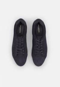 Navy suede sneakers with a low-top design, round toe, and lace-up closure. Features light-colored rubber sole and textured vamp.