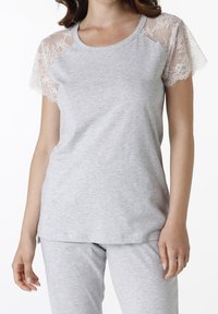 T-shirt grigia con maniche corte in pizzo, scollo rotondo e vestibilità morbida. Il tessuto è morbido con una superficie liscia. Abbinato a pantaloni grigi.