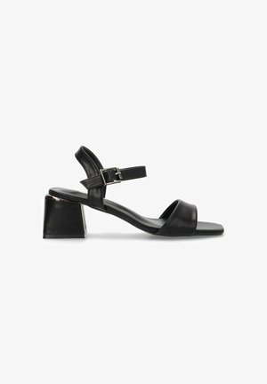 Sandalias de tacón en bloque de cuero negro con una correa ajustable en el tobillo. Cuentan con una textura suave y un diseño minimalista con una banda frontal ancha.