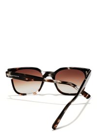 Ochelarii de soare Hawkers au o ramă texturată de tortoise brown, cu lentile degrade de culoare maro. Designul este unghiular, cu brațe drepte.