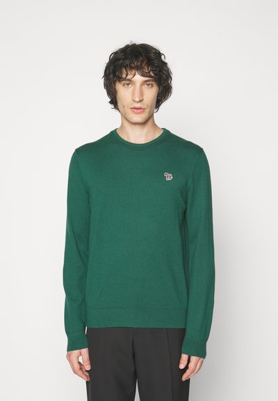 Green knit sweater with long sleeves, round neckline, and a small embroidered logo on the chest. Smooth texture, close-fitting design.