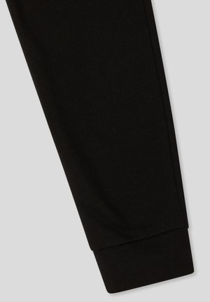 Czarne dresowe spodnie z bawełny z prążkowanym mankietem. Gładka struktura, dopasowany krój, brak widocznych wzorów czy elementów metalowych.