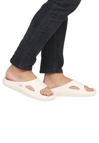 Open-toe slide sandals in beige, made from smooth rubber, featuring cut-out details and a textured sole for grip.