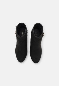 Botines de ante negro con textura suave, punta redondeada y cierre de cremallera lateral. Presentan un pequeño detalle dorado cerca del tobillo.