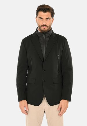 Giacca ibrida nera con design strutturato da blazer, dotata di uno strato interno con zip, due tasche laterali e tessuto strutturato.