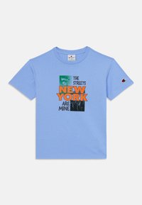 Ljusblå bomulls t-shirt med korta ärmar. Innehåller grafisk text "GATORNA I NEW YORK TILLHÖR MIG" i orange och svart. Champion-logotyp på ärmen.